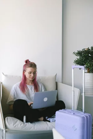 femme travaille sur son ordinateur et valise prête pour les vacances